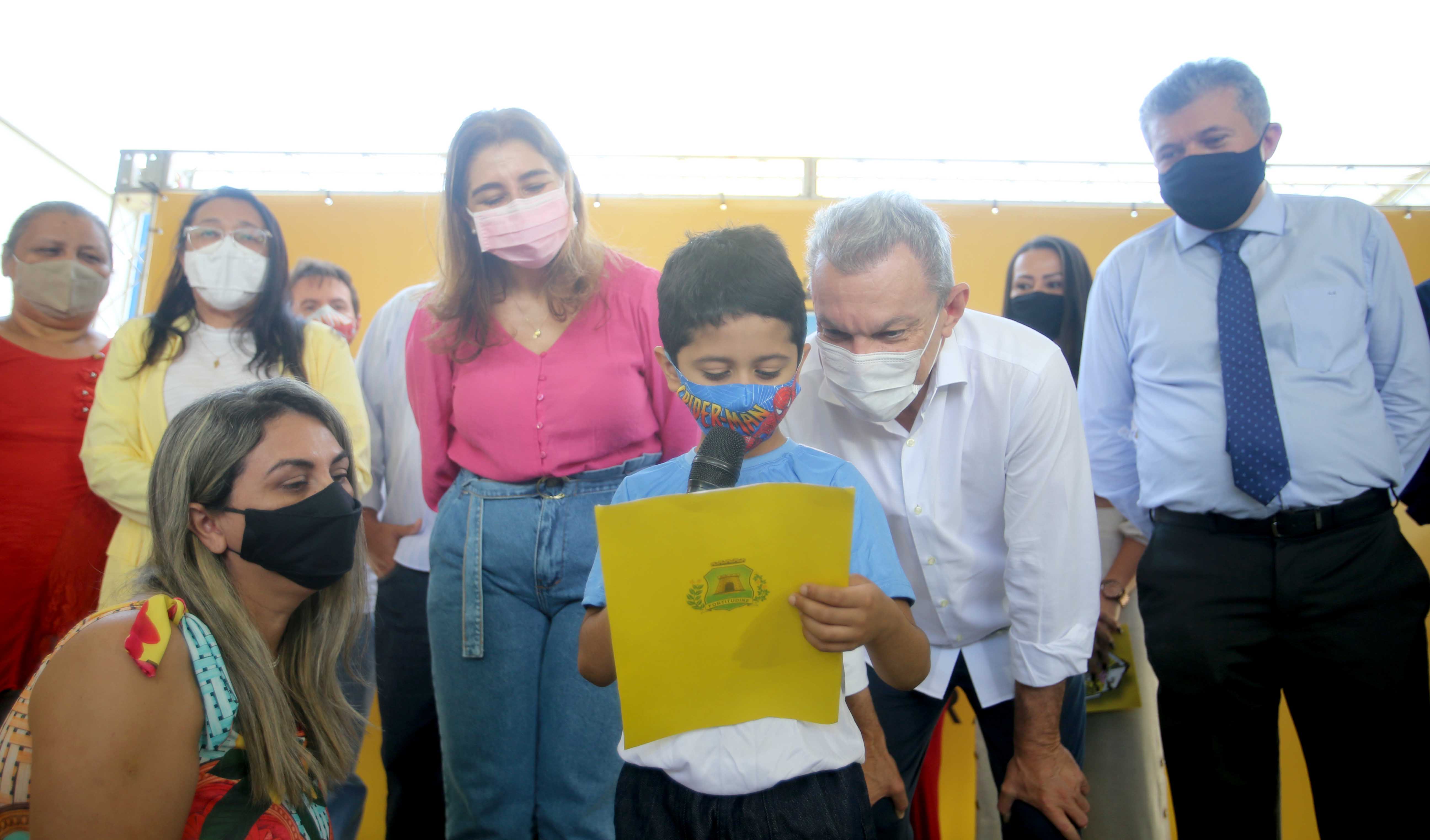 prefeito observa um estudante lendo um poema